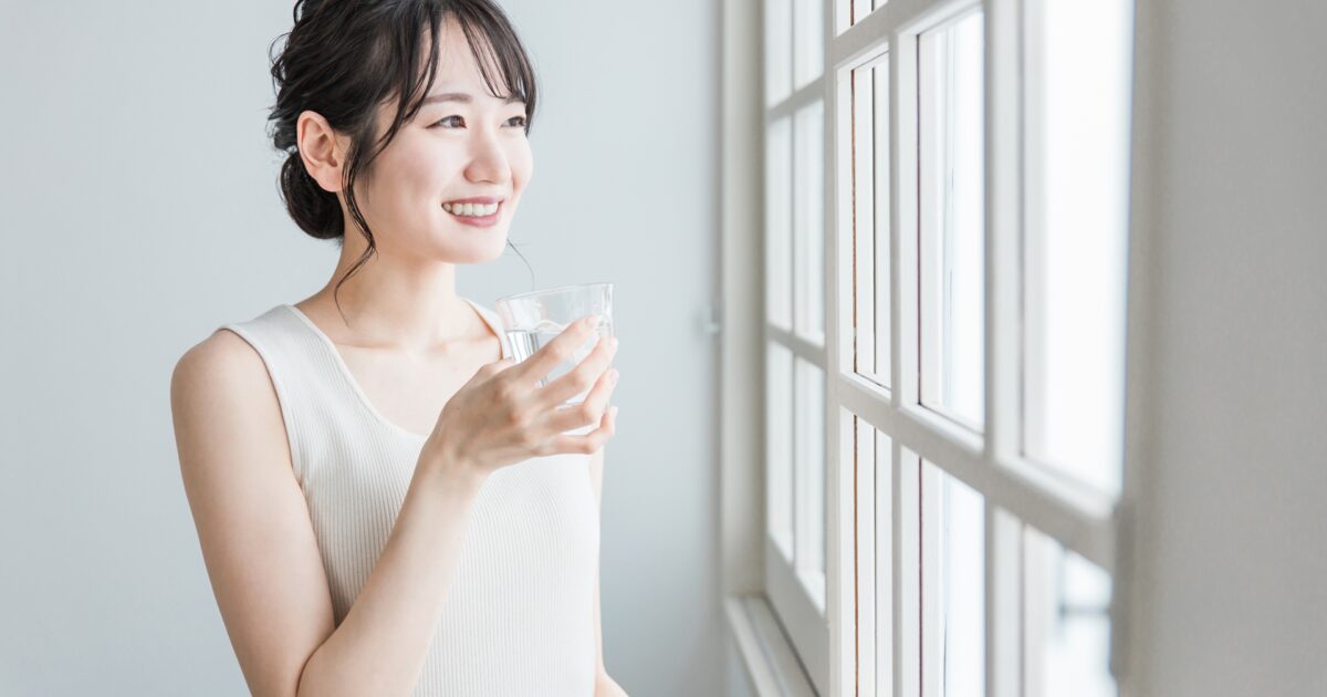 窓際で水を飲む女性