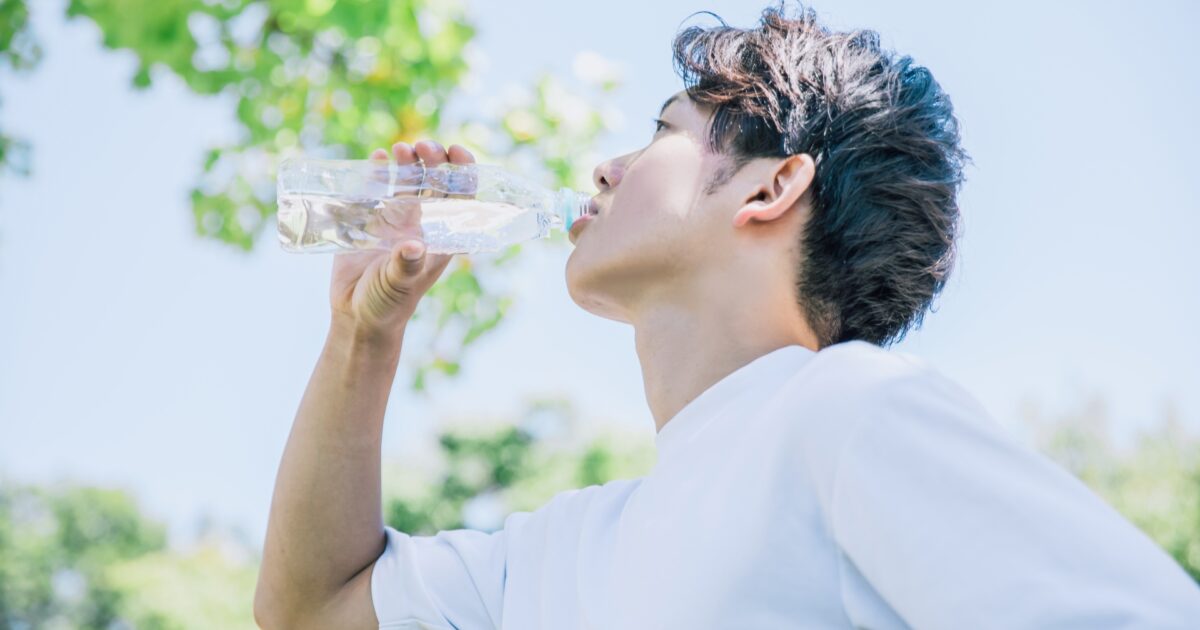 屋外でペットボトルの水を飲む男性