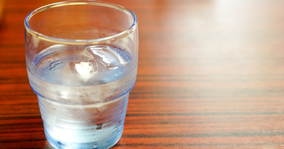 木製テーブルに置かれた氷水の入ったコップ