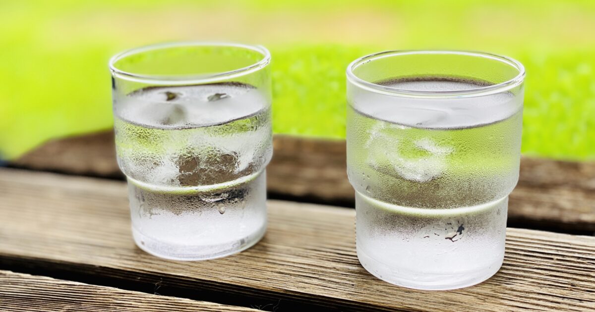 屋外のテーブルに置かれた氷水の入った二つのグラス