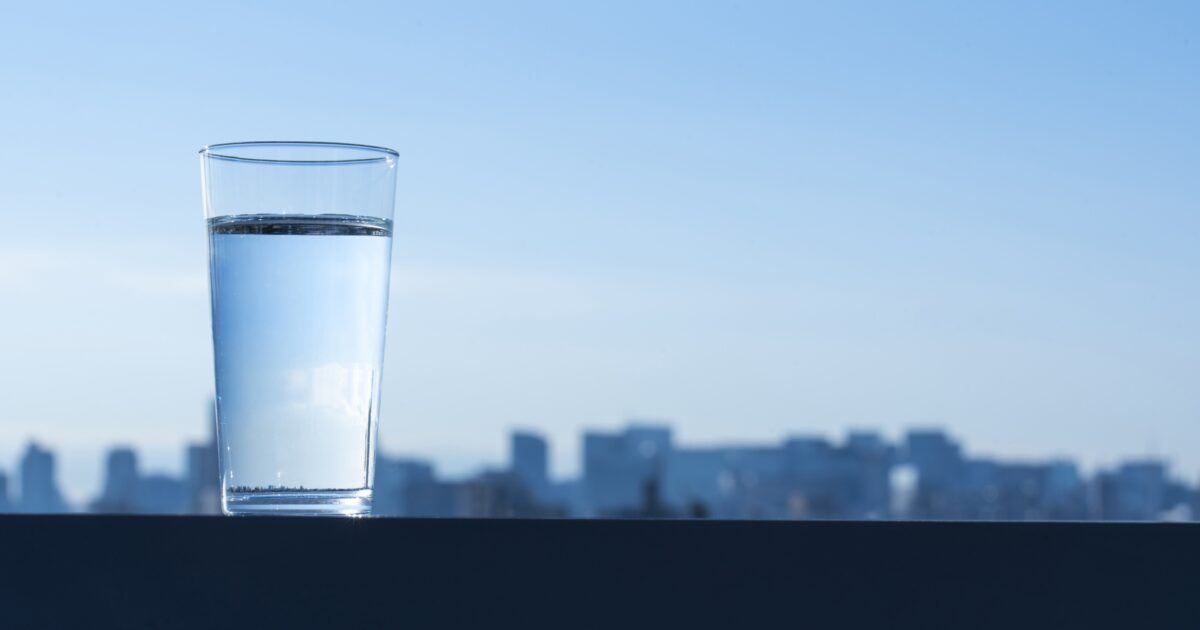 都市の景色を背景にした水の入ったグラス