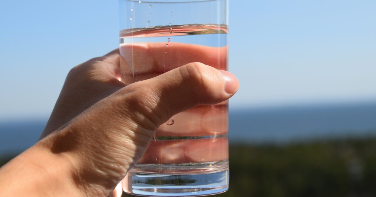 屋外で水の入ったグラスを手に持つ様子