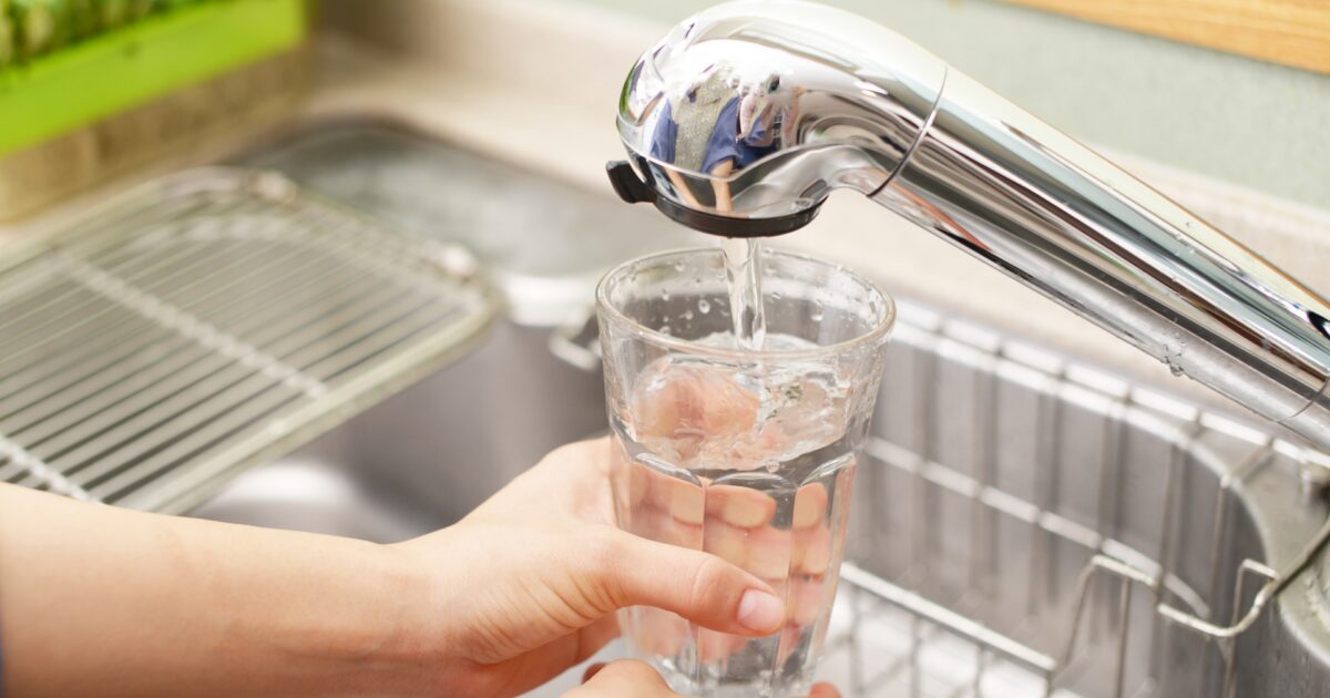 蛇口からグラスに水を注いでいる様子